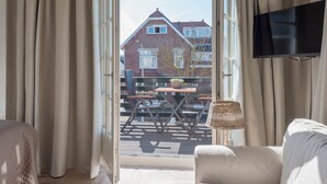 A room with a view of a brick house, a table with chairs, and a TV mounted on the wall.