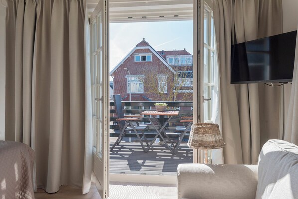 A room with a view of a brick house, a table with chairs, and a TV mounted on the wall.