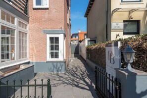 Een smalle steeg met een gebouw van baksteen aan de linkerkant en een beige gebouw aan de rechterkant. Er staat een bord met 'Mevira Apartments' en een bord met 'Pension Benne'.
