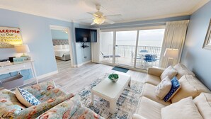 Un salón decorado con motivos playeros, que incluye un sofá, una mesa de centro y un televisor.