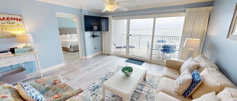 A beach-themed living room with a sofa, coffee table, and a TV.