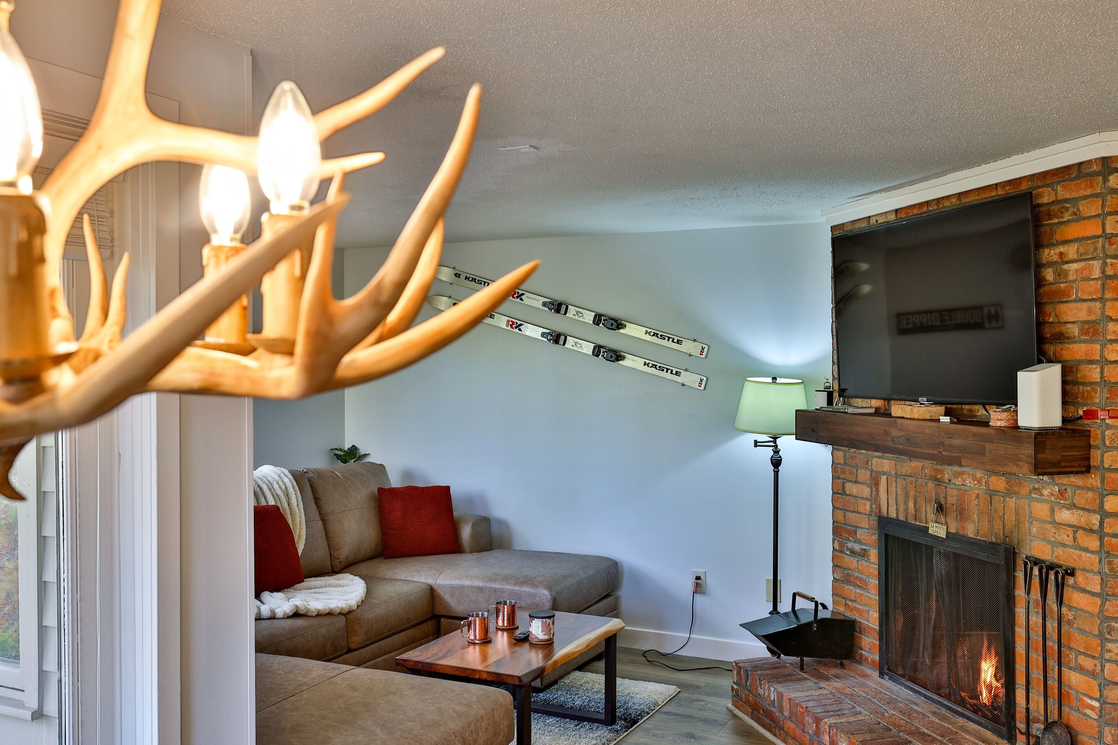 A living room with a brick fireplace, a sofa, a coffee table, and a chandelier.