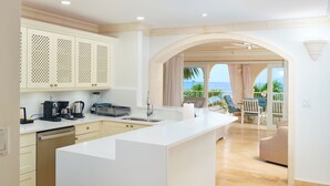 Una cocina moderna con una isla grande, un comedor con vista al océano y un balcón con mobiliario de exterior.