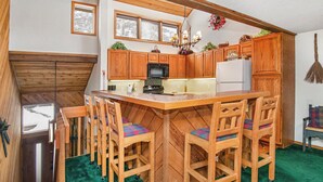 A kitchen with wooden cabinets, a central island with chairs, a refrigerator, and a stove. - Beaver Creek Townhome w/ Amenities | RP187 Stays limited to a max of 14 nites (Beaver Creek)