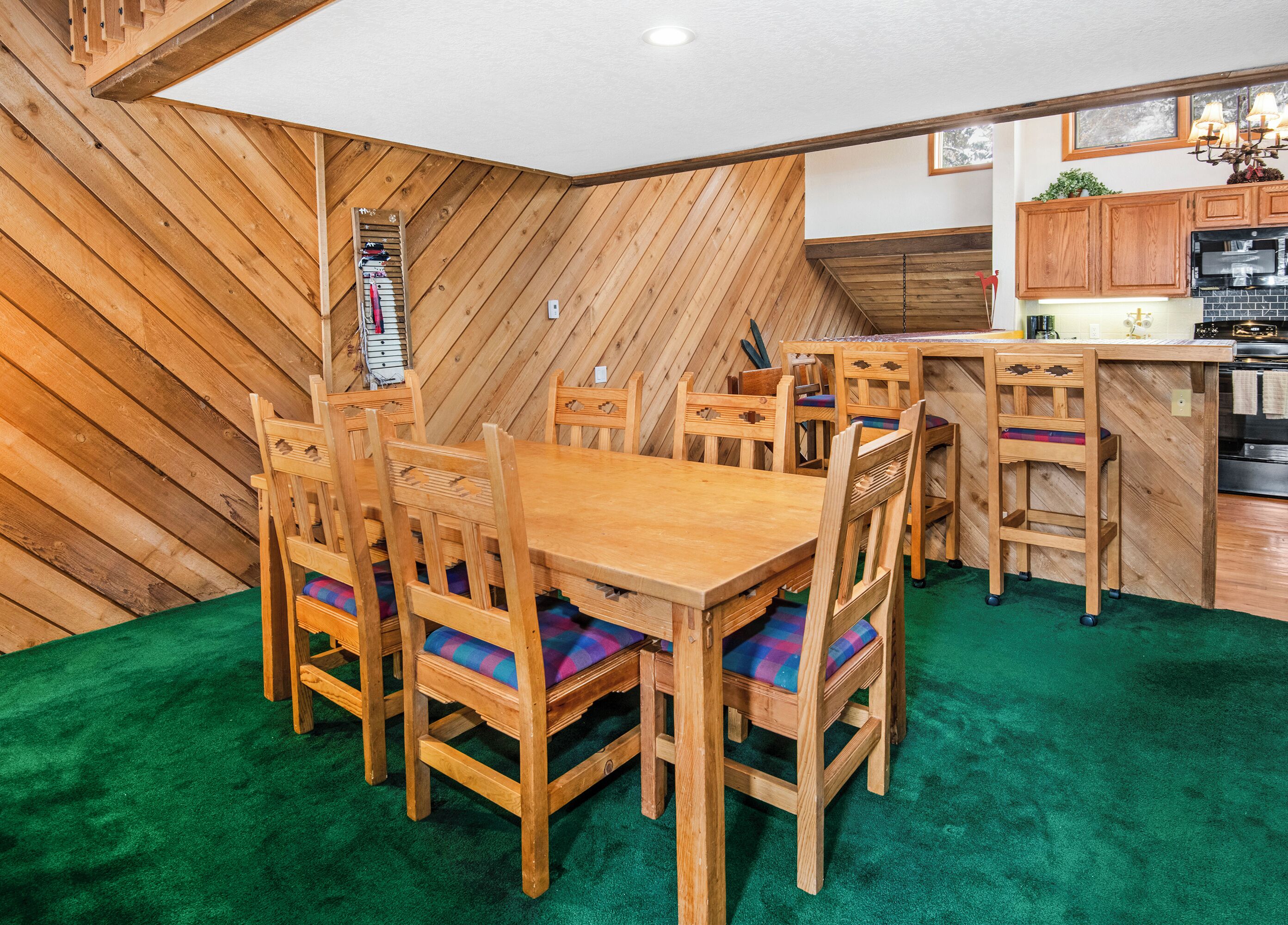 A dining area with wooden furniture and a green carpet.