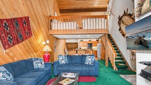 A cozy living room with two blue sofas, a glass coffee table, and a red rug. A wooden staircase leads to a loft bedroom. - Beaver Creek Townhome w/ Amenities | RP187 Stays limited to a max of 14 nites (Beaver Creek)