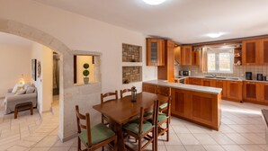 Una cocina moderna con armarios de madera, una isla central y un área de comedor con sillas acolchadas de color verde.