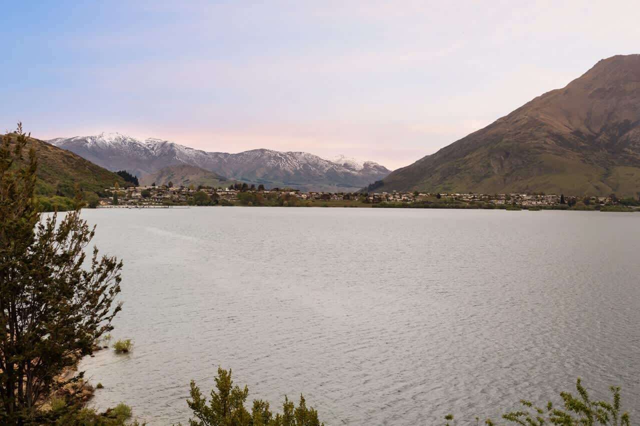 Un lago con montañas al fondo y un pueblo al otro lado del agua.