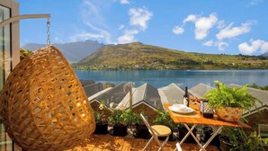 A terrace with a table set for dining, potted plants, and a hanging light fixture. - Lakefront, Mountain Views, Stylish unit (Queenstown)