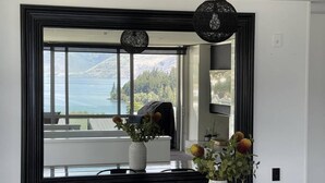 A modern interior with a large mirror reflecting a scenic view of mountains and a lake. - Central Lakeview Apartment | Walk to Town | Spa (Queenstown)