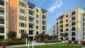 A multi-story residential building with balconies, large potted plants, and a well-maintained lawn. - LUX  La Mer Infinity View-Luxury Boho 1 (Dubai)