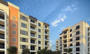 A multi-story residential building with balconies, large potted plants, and a well-maintained lawn. - LUX  La Mer Infinity View-Luxury Boho 1 (Dubai)