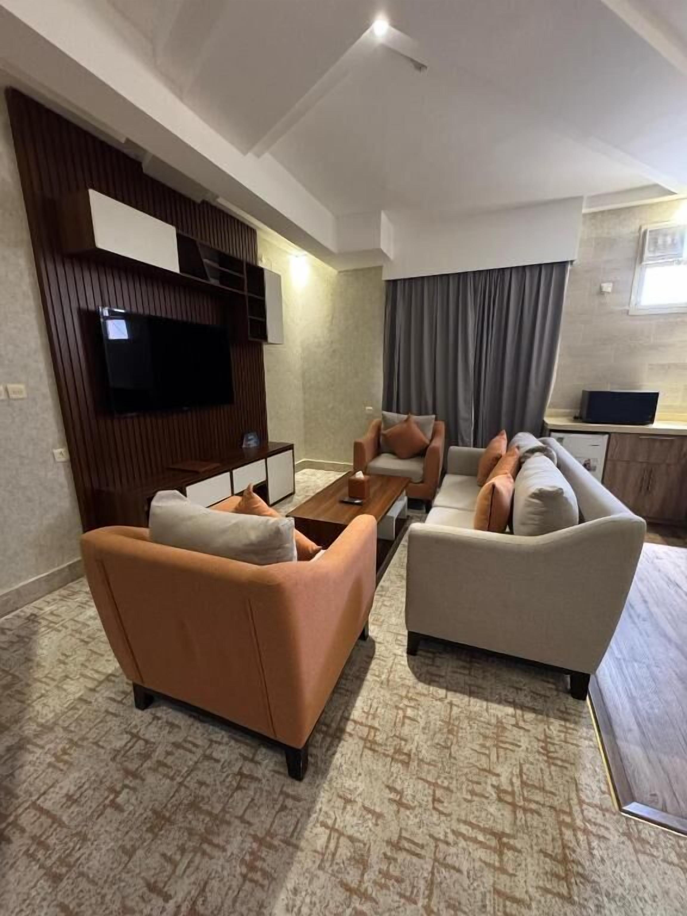 A modern living room with two sofas, a coffee table, and a flat-screen TV mounted on a wooden panel.