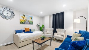 A modern living room with a sofa, armchairs, a coffee table, a wall clock, and a painting. - Colorful 5BR 3BA in Oakland, near Pitt & CMU (Pittsburgh)