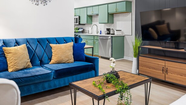 A modern living room with a blue sofa, a wooden coffee table, and a TV stand. - Colorful 5BR 3BA in Oakland, near Pitt & CMU (Pittsburgh)