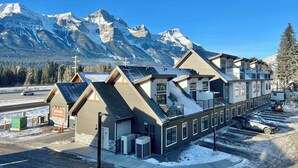 Un hotel con varias construcciones, una zona de estacionamiento y vistas a montañas nevadas.