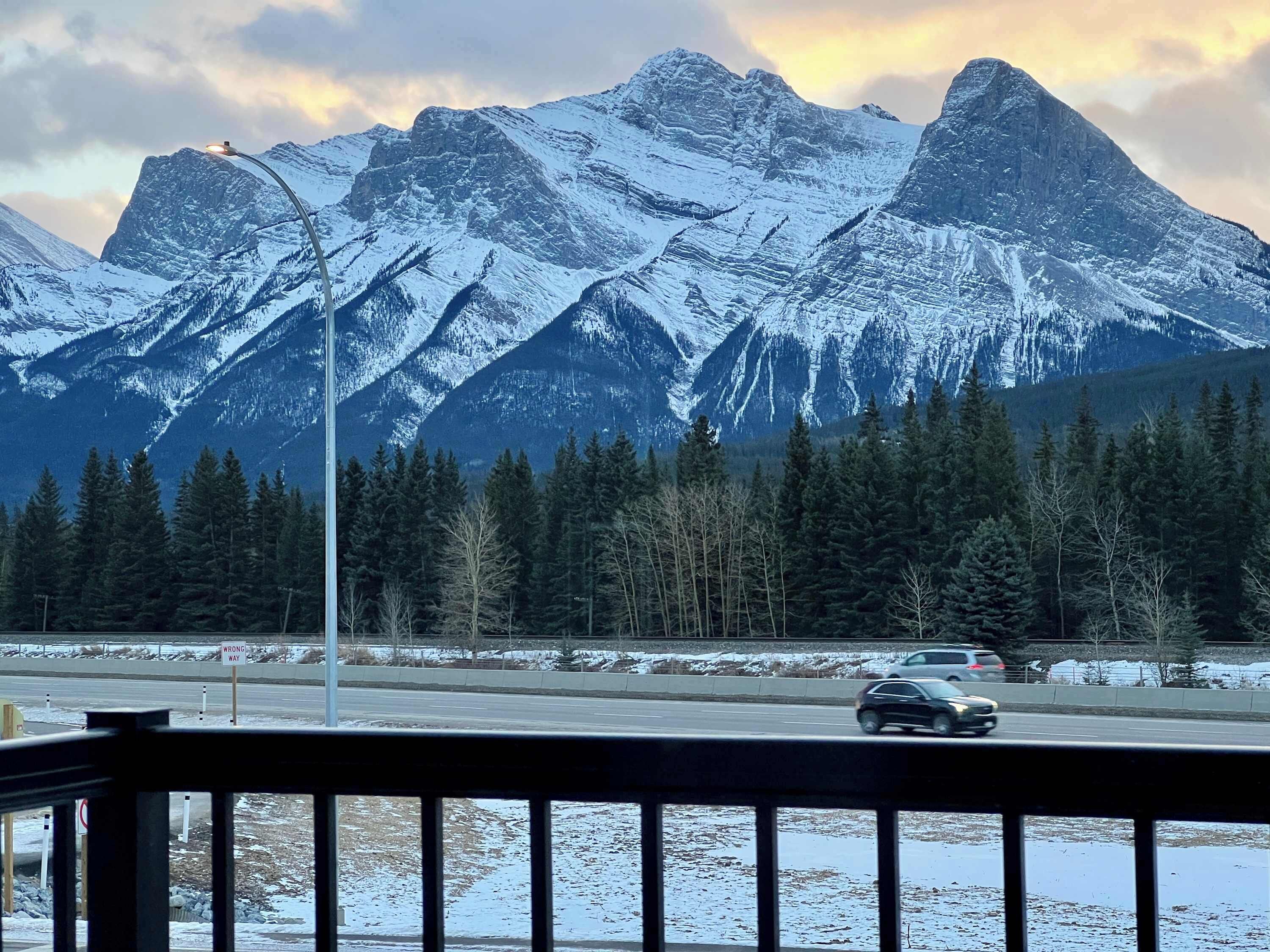 A mountain landscape with snow-covered peaks and a road with vehicles.