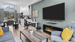 Una sala moderna con chimenea, sofás grises, una mesa de centro y un televisor de pantalla plana.