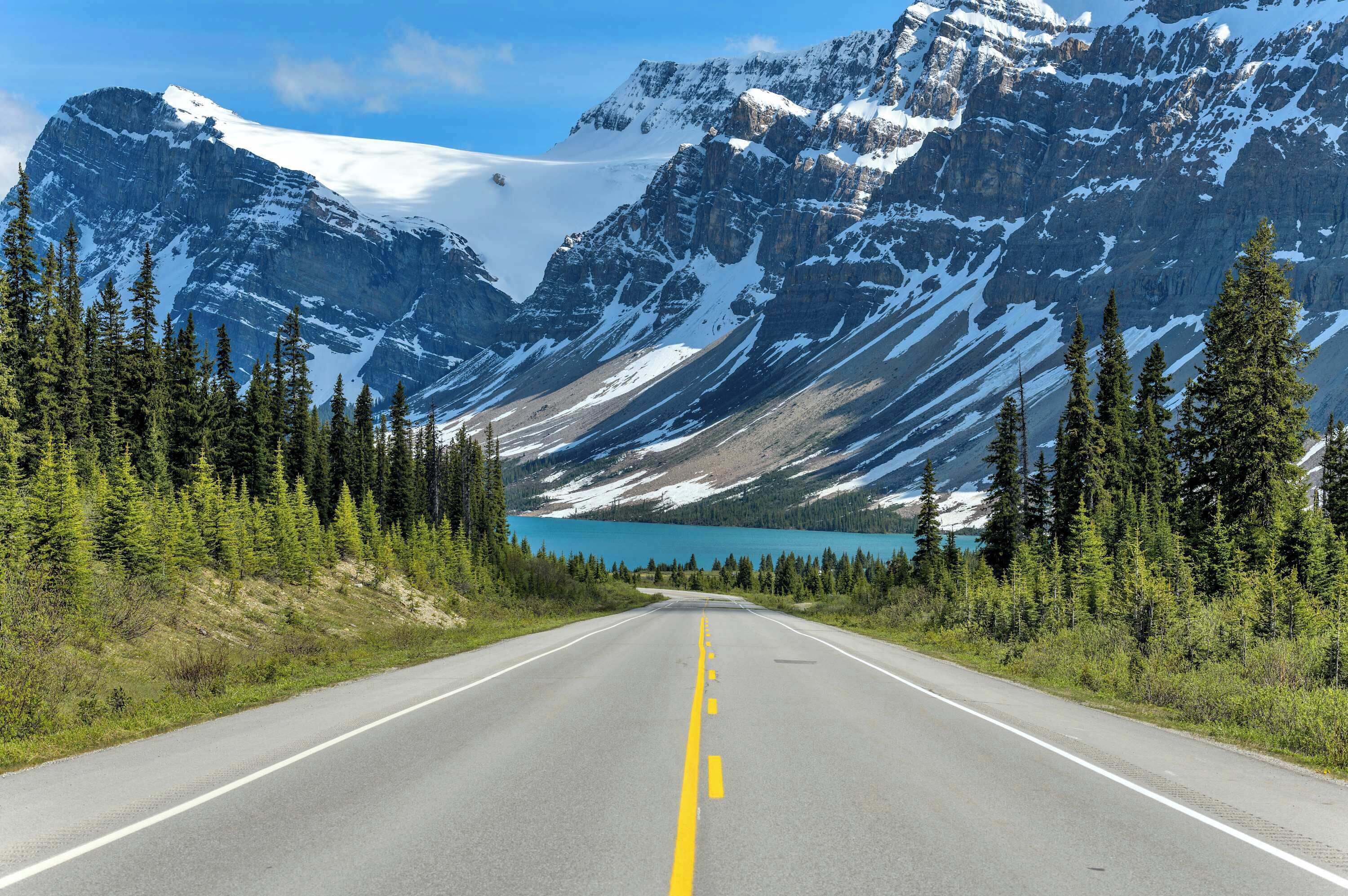 Une route menant à un paysage montagneux avec un lac.
