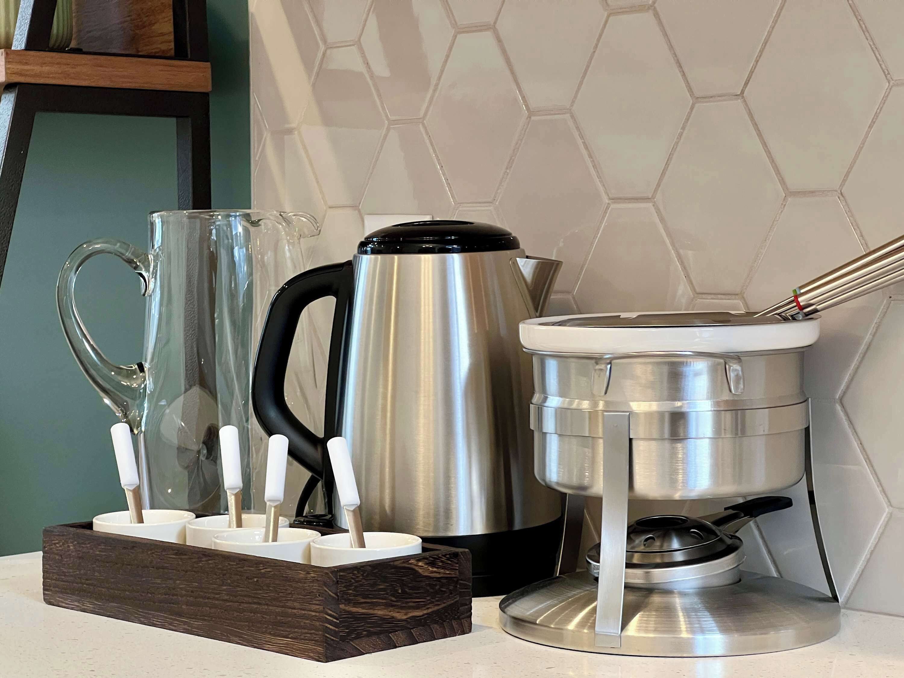 A kitchen counter with a coffee maker, a glass pitcher, and a mug holder.