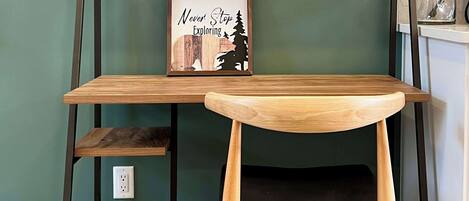 Un escritorio de madera con una silla negra, una cita inspiradora enmarcada y una pequeña figura en la estantería.