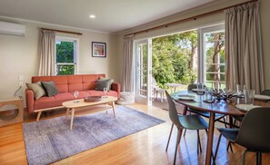 A living room with a red sofa, a coffee table, and a dining area with a table and chairs.