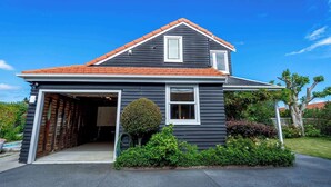 Een tweelaags huis met garage, een kleine voortuin met een verzorgd gazon en een grote boom.