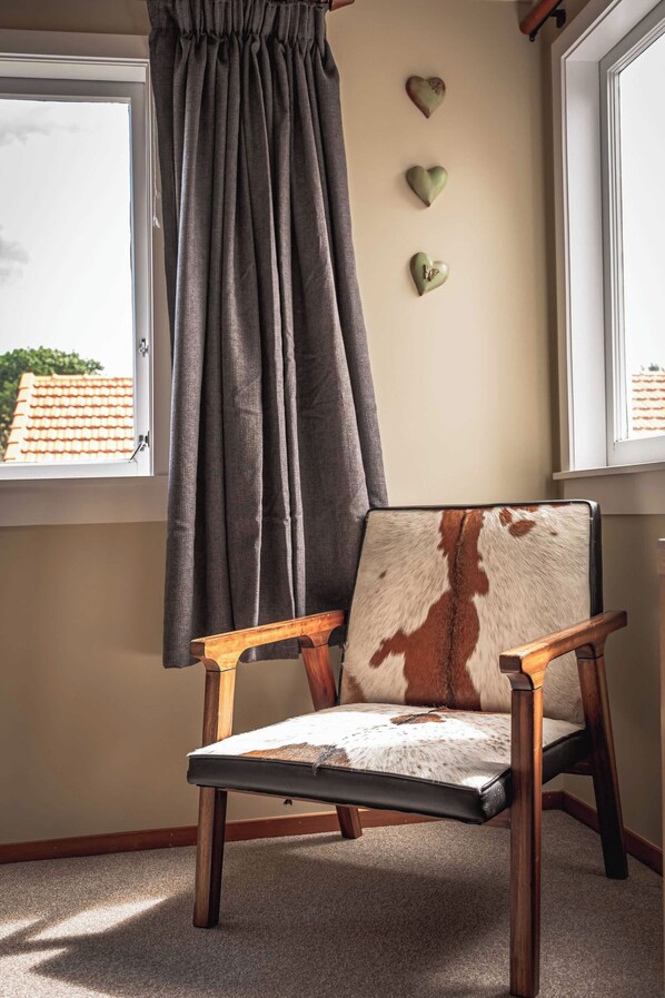 A chair with a leather and fur design, positioned near a window with a view of a tiled roof outside.