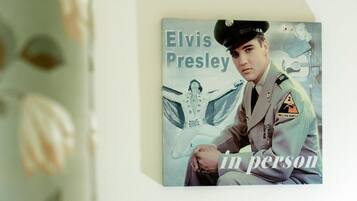 Portada de álbum enmarcada de Elvis Presley titulada 'In Person', con un uniforme militar y una guitarra de fondo.