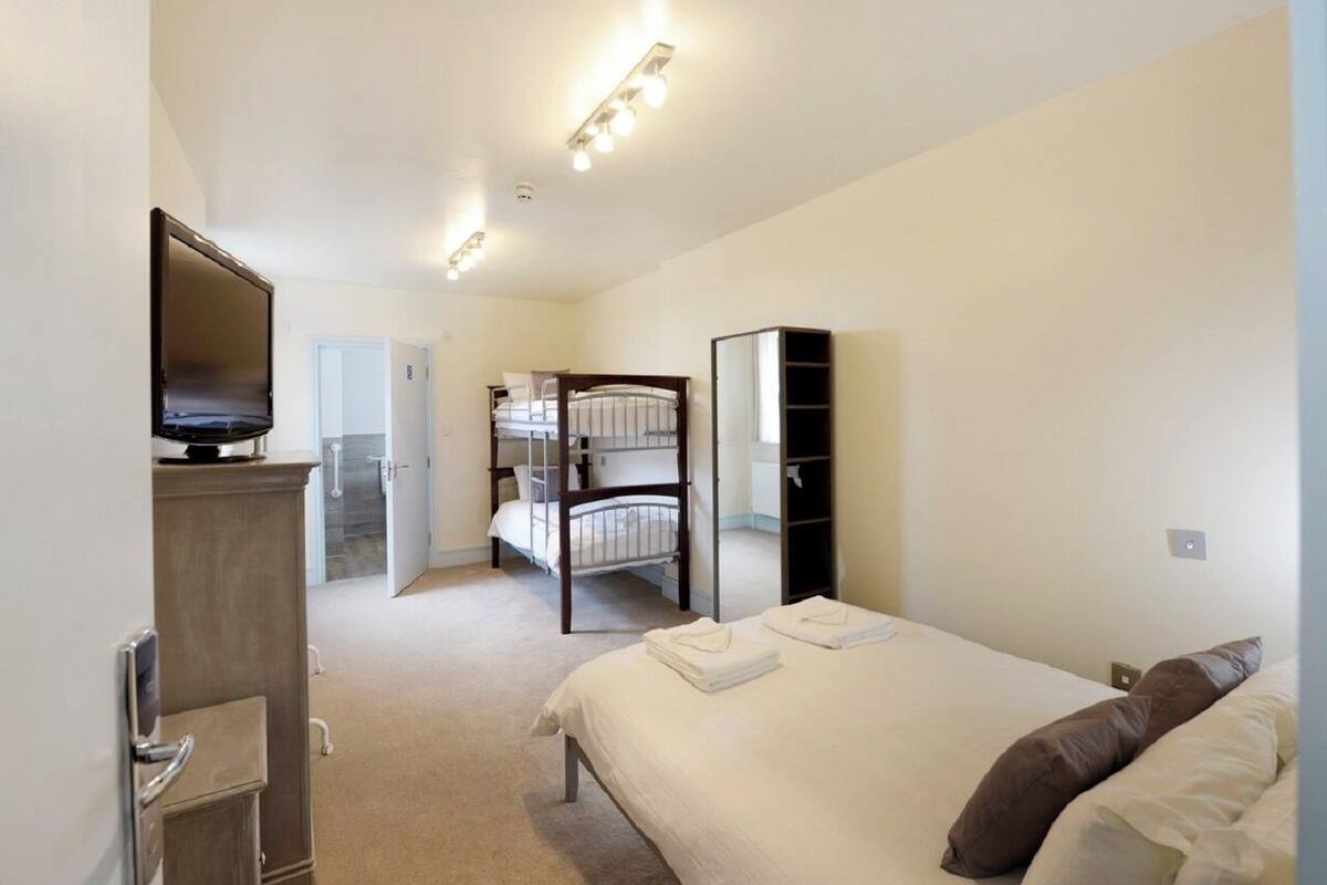 A hotel room with a bed, a TV, a wardrobe, and a mirror.