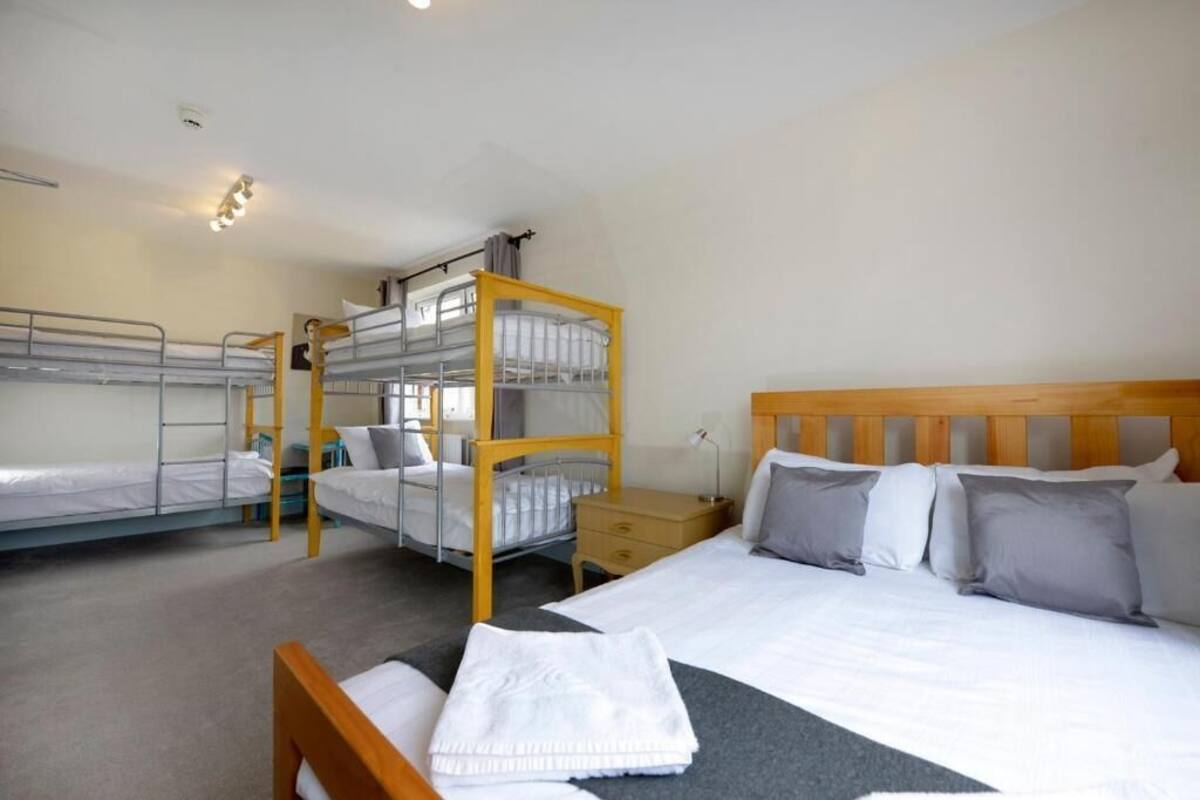 A dormitory room with bunk beds, a single bed, and a wooden headboard.
