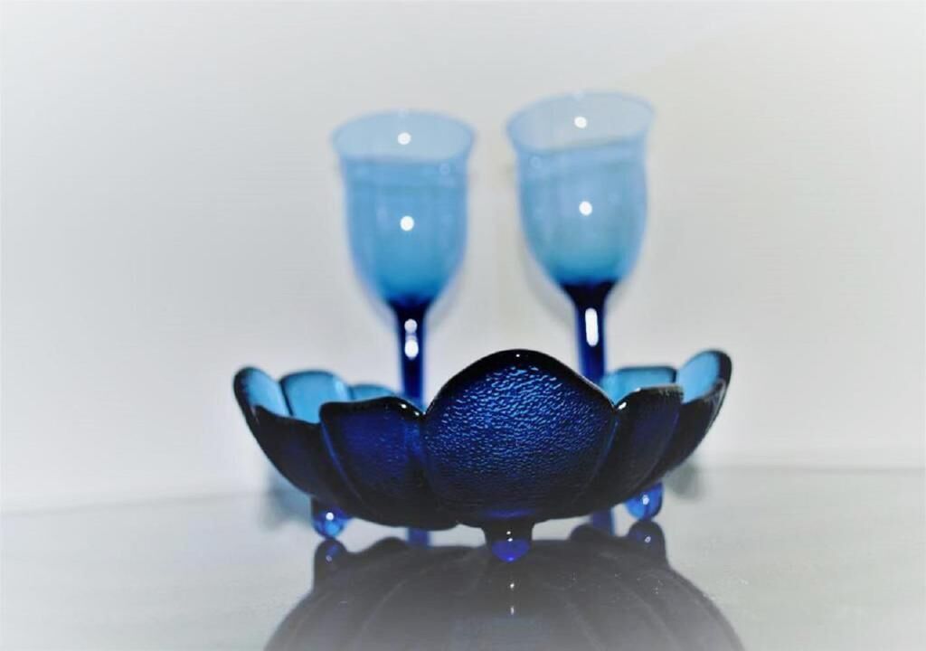 Un ensemble de verres bleus posés sur une surface réfléchissante.