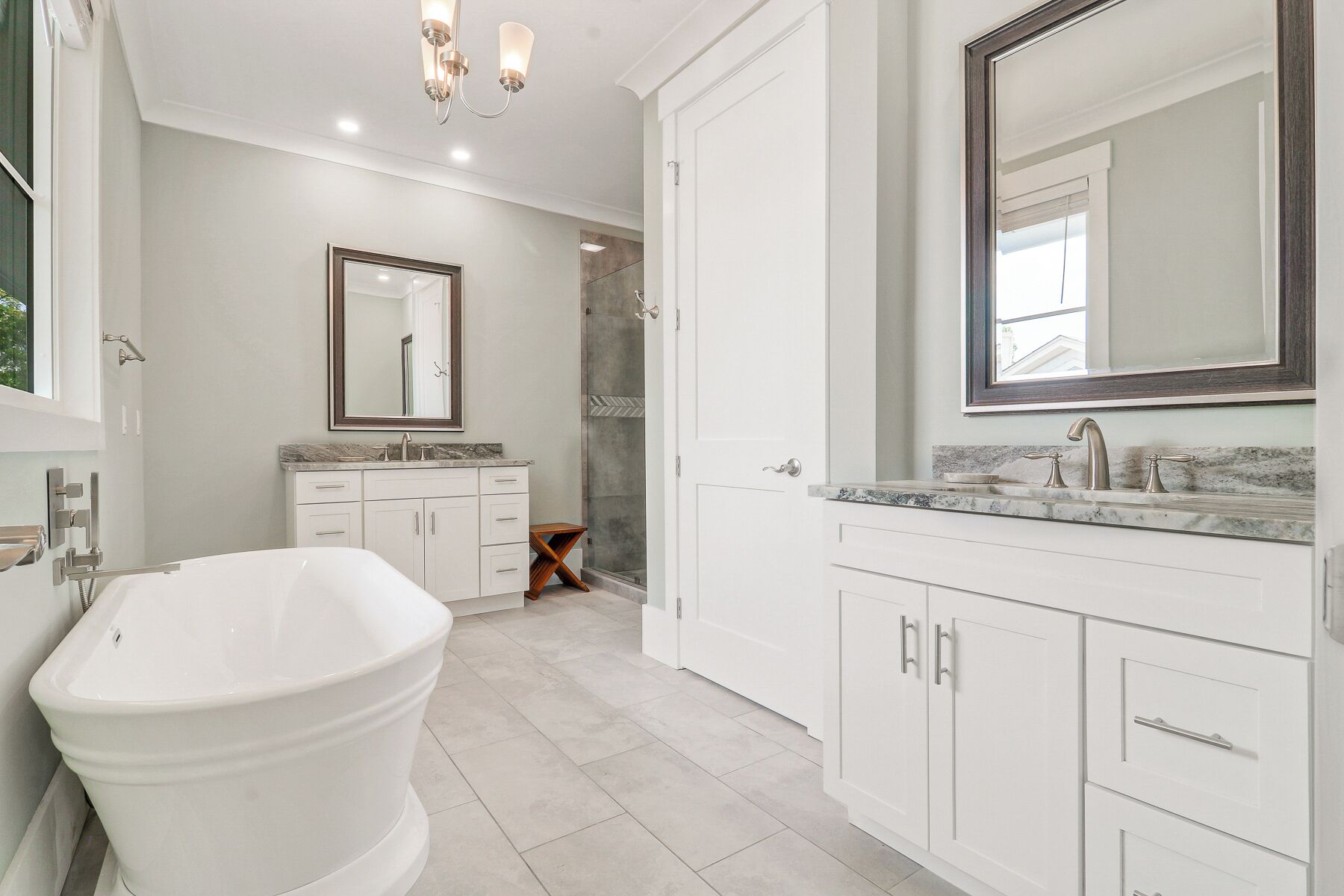 A modern bathroom with a freestanding bathtub, a large mirror, and a walk-in shower.