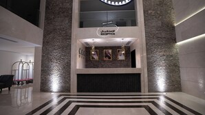 Un espace d’accueil au design moderne, comprenant un comptoir de réception, des portraits encadrés et un motif géométrique sur le sol.