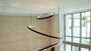 Un hall d’entrée moderne doté d’une grande baie vitrée, d’un sol à motifs en noir et blanc et d’un luminaire circulaire original.