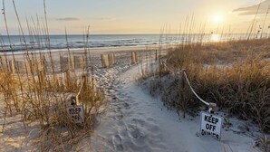 Un sendero en la playa con carteles que dicen 'KEEP OFF DUNES' y 'KEEP OFF DUNES'.