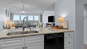 Una cocina moderna con lavavajillas integrado, un amplio ventanal con vistas al mar y un comedor.