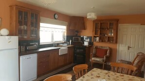 Eine kompakte Küche mit Holzschränken, einem Kühlschrank, einer Mikrowelle und einem Essbereich mit Tisch und Stühlen.