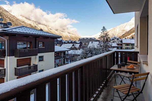 A balcony with a view of a snow-covered village and mountains.