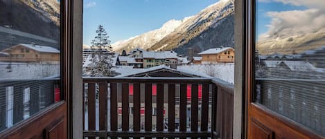 A balcony with a view of a snowy mountain landscape and buildings.
