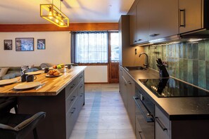 A modern kitchen with a wooden island, stainless steel appliances, and a view of the city through large windows.