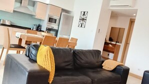 Un soggiorno moderno con un divano nero, una coperta gialla e un'area pranzo con sedie di legno e un tavolo.