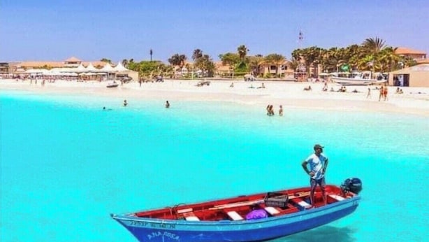 Una piccola barca su una spiaggia turchese con cielo sereno.