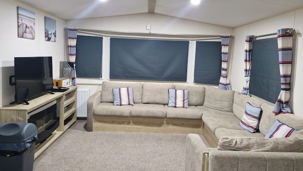 A cozy living room with a sofa, a TV, and a radiator. - Highfield Grange Holiday Park (Clacton-on-Sea)