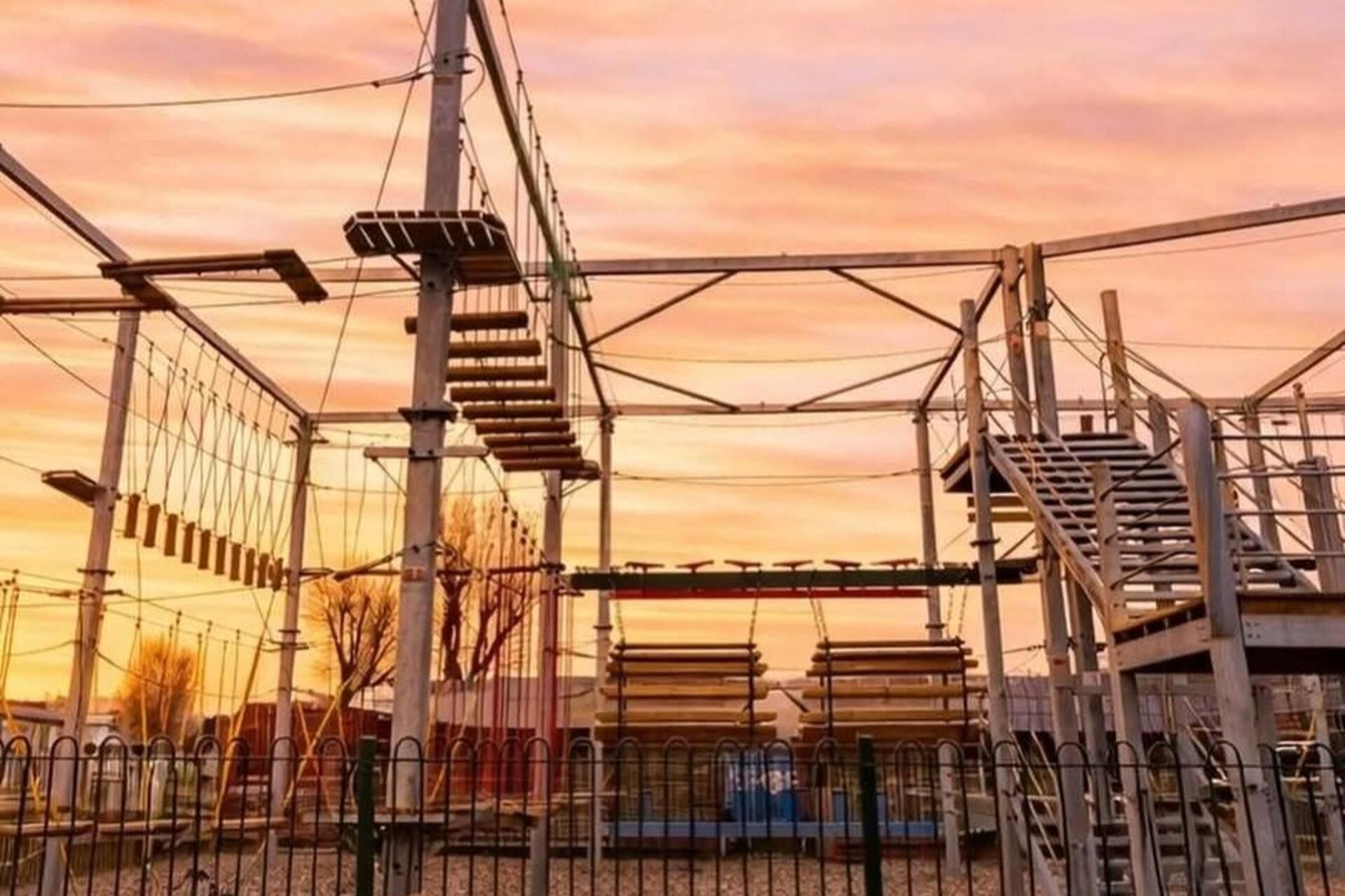 A metal climbing structure with multiple levels and ladders, surrounded by a metal fence.