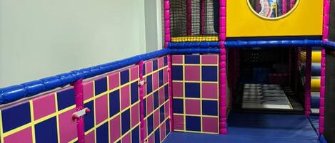 A colorful indoor play area with a blue floor, pink and blue walls, and a yellow ceiling.
