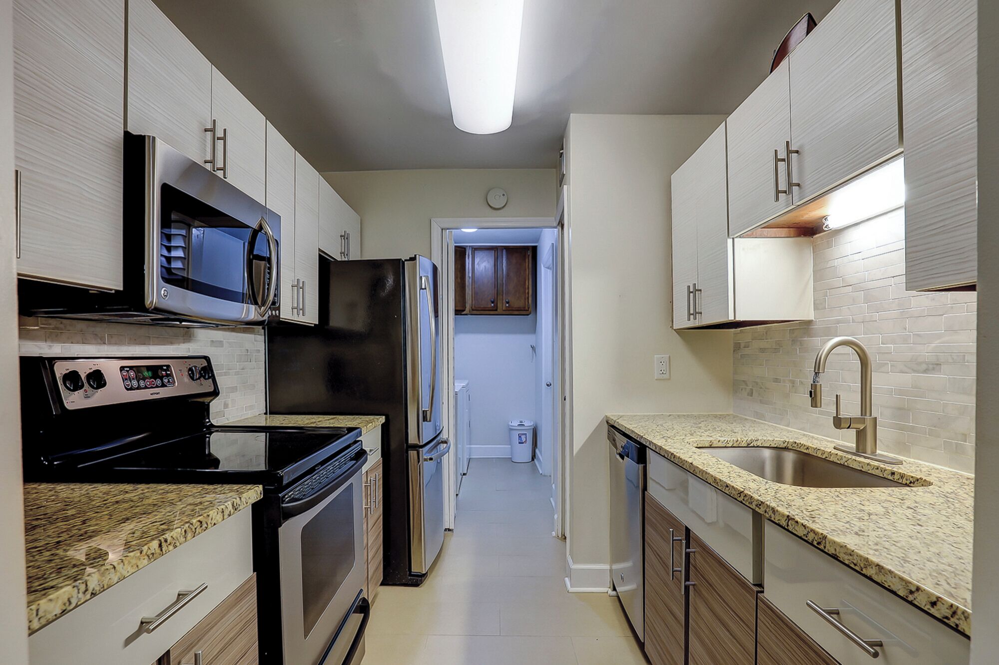 Una cocina moderna con electrodomésticos de acero inoxidable, encimeras de granito y una despensa amplia.