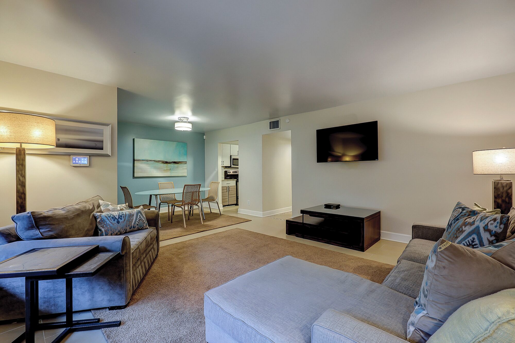 A living room with a sofa, a coffee table, a TV, and a painting on the wall.