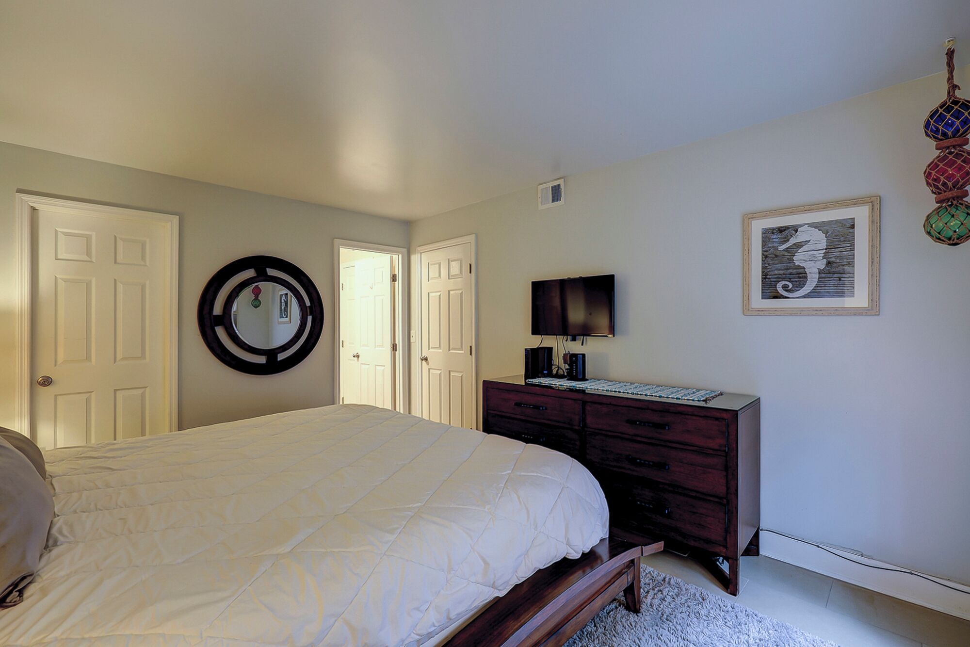 Una camera da letto con un letto, una cassettiera, una TV e un quadro appeso al muro.