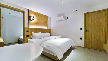 A modern hotel room with a large bed, a bedside table, a mirror, and a wooden wardrobe.